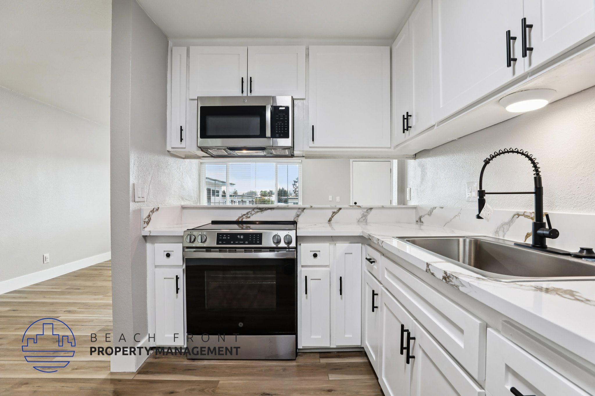A kitchen with white cabinets and a black faucet.
